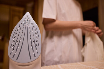 A person meticulously ironing clothes at home, ensuring all garments are neat and well cared for