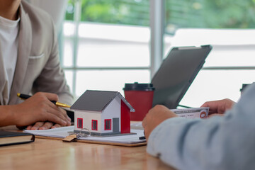 Fototapeta premium Middle-aged male real estate agent in office analyzes housing documents, signs apartment sale contract, discusses loans, investments, mortgages and property deals with clients.