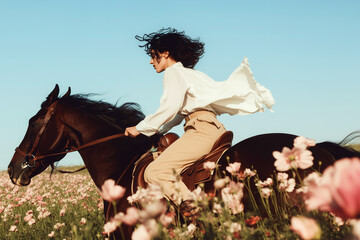 Confident Woman Riding Horse Through Flower Field at Golden Hour