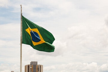 Bandeira do Brasil tremulando hasteada no topo de um mastro. 