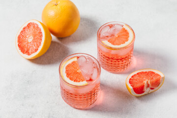 A refreshing pink negroni cocktail with ice served in a textured crystal glass, garnished with a...