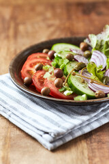 Salad with Olives, Tomatoes and Cucumber on wooden Background. Healthy Snack Idea. Close up.