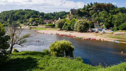Limeuil, France: tourist families enjoying water sports in Dordogne River, paddling in canoes and swimming in wild water, listed as one of the Most Beautiful Villages in France