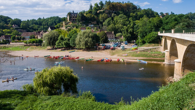 Limeuil, France: tourist families enjoying water sports in Dordogne River, paddling in canoes and swimming in wild water, listed as one of the Most Beautiful Villages in France