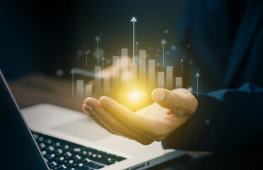 Businessman holding glowing bar graph with upward arrows, symbolizing financial growth, success, data analytics, and digital transformation in modern business.