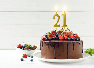 Yummy chocolate cake with fruits and burning number shaped candles on white table, space for text....