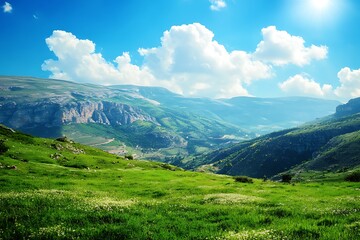 Fototapeta premium Landscape of green meadows and mountains under blue sky with clouds
