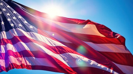 American flag waving against a blue sky with the sun shining through it creating lens flare