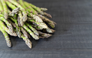 Neatly arranged green asparagus spears on a black wooden surface, clean and textile-free