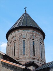 Conical dome rising above the brick walls of an orthodox church in Georgia