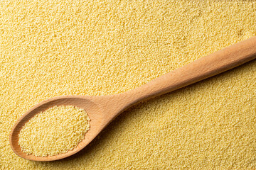 Couscous grains scooped up by a wooden spoon