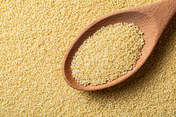 Couscous grains scooped up by a wooden spoon