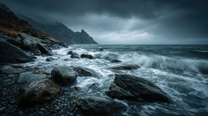 Obraz premium A dramatic seascape featuring powerful waves crashing against a rocky shoreline under a dark, overcast sky. Jagged cliffs rise in the background, adding depth and tension to the moody scene