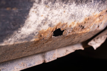 Deep rust on the body of a gray old car. Rust and corrosion hole on old worn out painted metal...