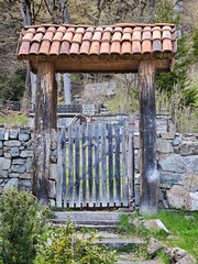 Old wooden gate with tiled roof leading to garden