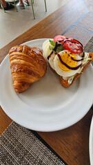 Delicious Breakfast with Croissant sandwiches with Fried Egg, Salad Leaves, Grilled Mushrooms and Cherry Tomatoes