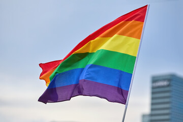 LGBTQ Pride Flag Waving. A vibrant rainbow flag fluttering against a clear sky