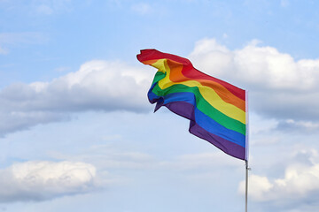 LGBTQ Pride Flag Waving. A vibrant rainbow flag fluttering against a clear sky