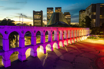 Lapa Aqueduct Illuminated With Purple and Pink Colors in the Evening With Tall Office Buildings of Rio de Janeiro Downtown