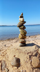 On the beach, on the sand, pebbles are placed on top of each other