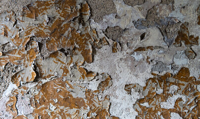Close-up of peeling paint on a rough concrete wall. Weathered texture and cracked surface create a gritty, urban, and abandoned look.