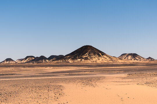 Ash-covered hills in Egypt's Black Desert under a clear sky, scenic and remote landscape. Volcanic
