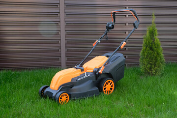 New electric lawn mower against the background of  country house lawn.