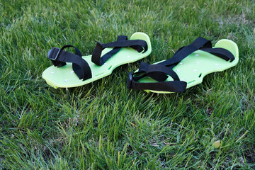 Lawn aeration device, shoe covers with metal spikes on the background of lawn grass