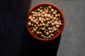 Earthenware bowl full of chickpeas on a kitchen worktop in a zenithal photograph
