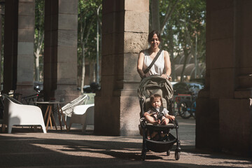 Obraz premium A woman is pushing a stroller with a baby in it
