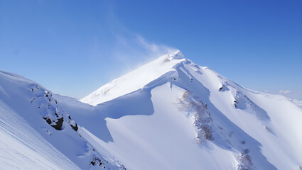 Majestic winter mountain peak with snowdrifts and clear blue sky