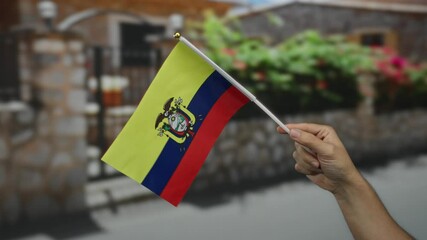 Man's hand holding ecuador flag in outdoor street setting with blurred background, showcasing national pride and diversity. - Powered by Adobe