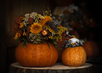 Autumn still life with pumpkins, flowers and a candle on a wooden base.