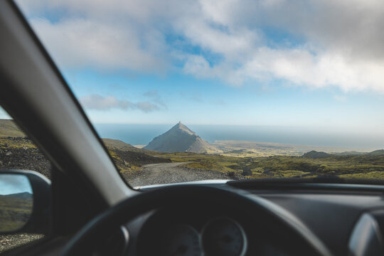 Driving along a rugged gravel road toward a striking mountain peak on Iceland Snaefellsnes Peninsula. A perfect moment of road trip freedom and adventure