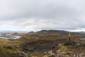 Lone hiker stands on the end of The Horn mountain on Snaefellsnes peninsula in Iceland as golden...