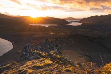 Lone hiker stands on the end of The Horn mountain on Snaefellsnes peninsula in Iceland as golden...