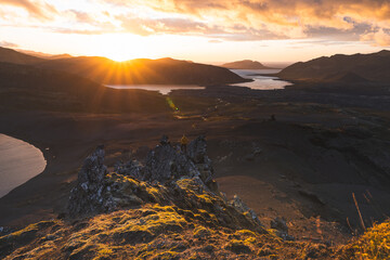Lone hiker stands on the end of The Horn mountain on Snaefellsnes peninsula in Iceland as golden...
