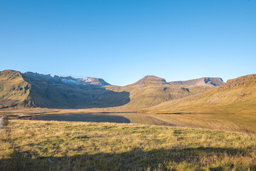 Golden mountains reflect in a still lake on Snaefellsnes peninsula Iceland with glacier capped...