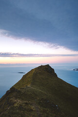 Lone hiker celebrates at the summit of Kirkjufell Mountain, Iceland, standing above the sea at sunrise symbolizing freedom, achievement, and connection with nature