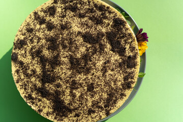 Poppy seed cake decorated with edible flowers on a green table background