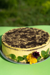 Poppy seed cake decorated with edible flowers on a green table background
