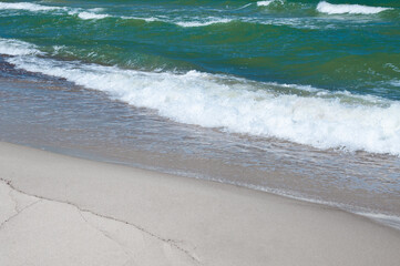 Sandy coastline and sea waves by summer day