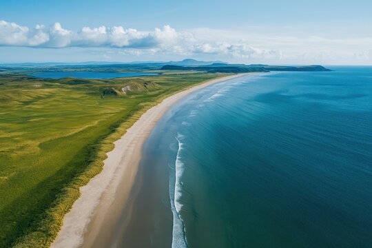 Aerial view of a coastal landscape with sandy beach and turquoise waters on a sunny day, Vertical aerial drone footage of a landscape with ocean and grass shore on the side