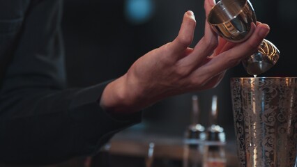 Closeup mixing hand bartender holding jigger to measure juice into shaker design preparation for mixed cocktail at bar. Special refresh drink showcasing nightlife mixology inviting at club. Vinosity.