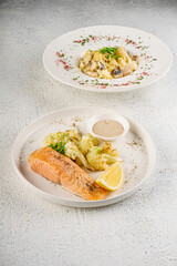 Grilled salmon fillet with broccoli and lemon on white plate