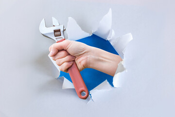 Hand with wrench emerging through wall.