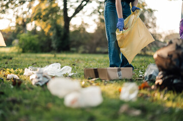 Volunteer picking up trash in public park wearing gloves