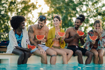 Friends eating watermelon by the poolside on summer vacation