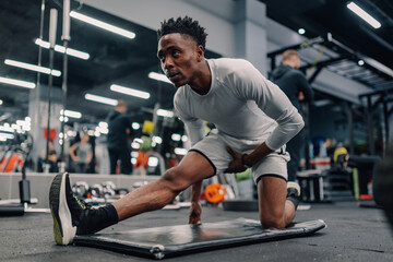 Young athlete stretching legs on mat in modern gym
