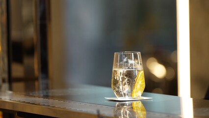 Serving welcome refreshing drink of fizzy tonic or soda with slide lemon at beverage counter bar of...